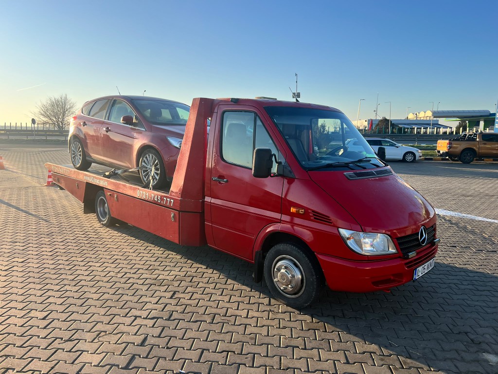 Autospecială de tractare cu un autoturism pe platformă.